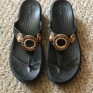 Crocs flip flops with black and gold embezzlement